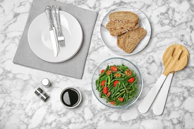 Tasty green beans with tomatoes served for dinner on marble table, top view