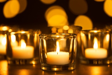 Photo of Burning candles on table against blurred background. Funeral symbol