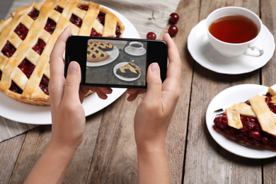 Blogger taking picture of pie and tea at table, closeup