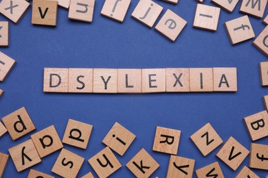 Photo of Word Dyslexia made with shuffled cubes on blue background, flat lay