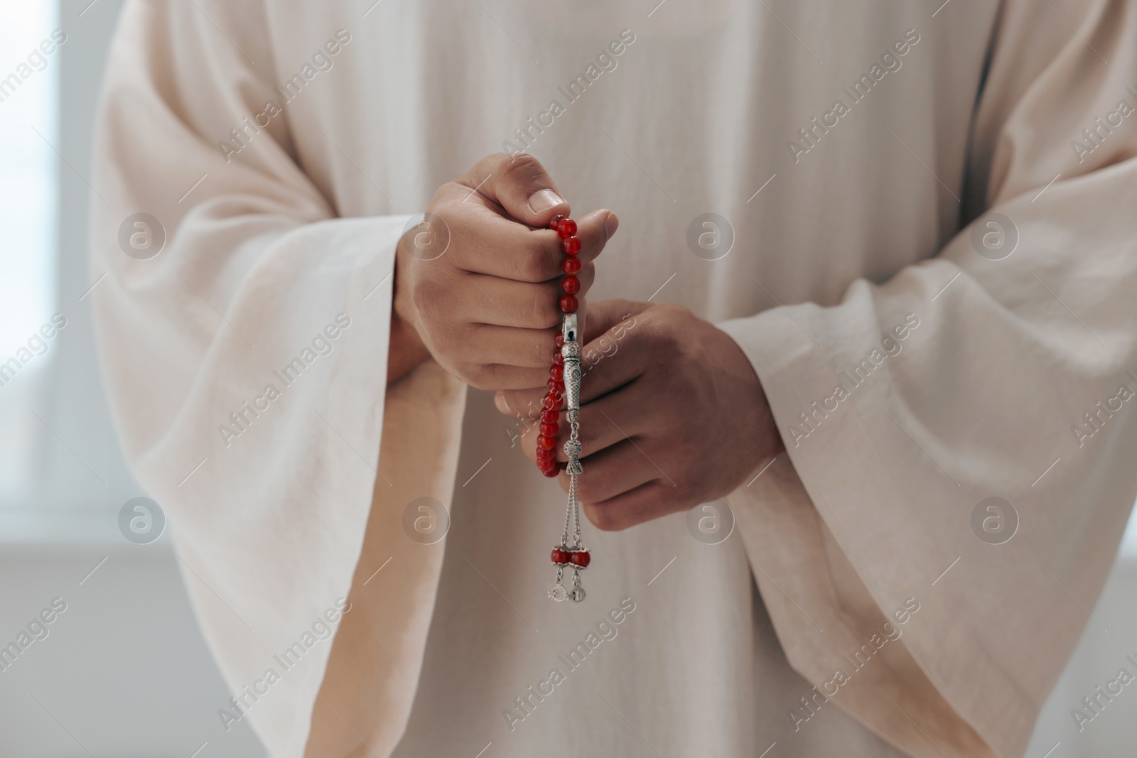 Photo of Muslim man with misbaha indoors, closeup view