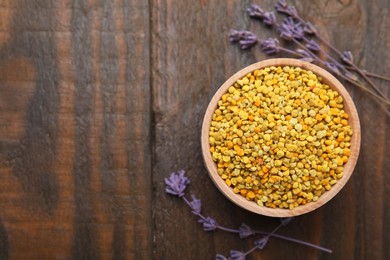 Photo of Fresh bee pollen granules and lavender on wooden table, top view. Space for text