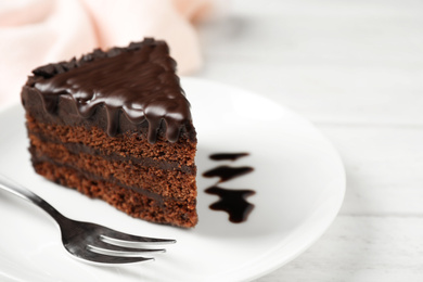 Tasty chocolate cake served on white wooden table, closeup. Space for text