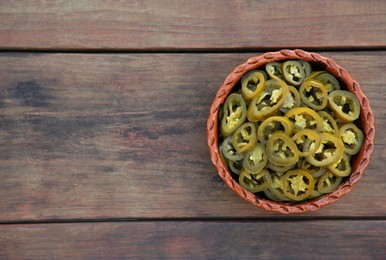 Photo of Pickled green jalapeno peppers on wooden table, top view. Space for text