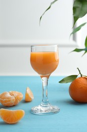 Photo of Delicious tangerine liqueur and fresh fruits on light blue wooden table