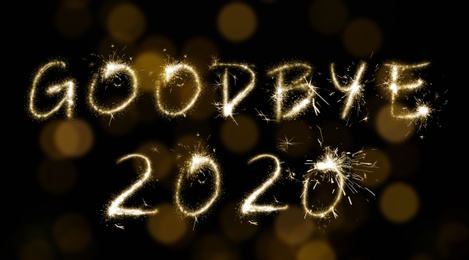 Image of  Goodbye 2020. Bright text made of sparkler on black background with blurred lights, banner design