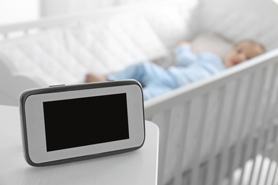 Photo of Baby monitor on table near crib with child in room. Video nanny