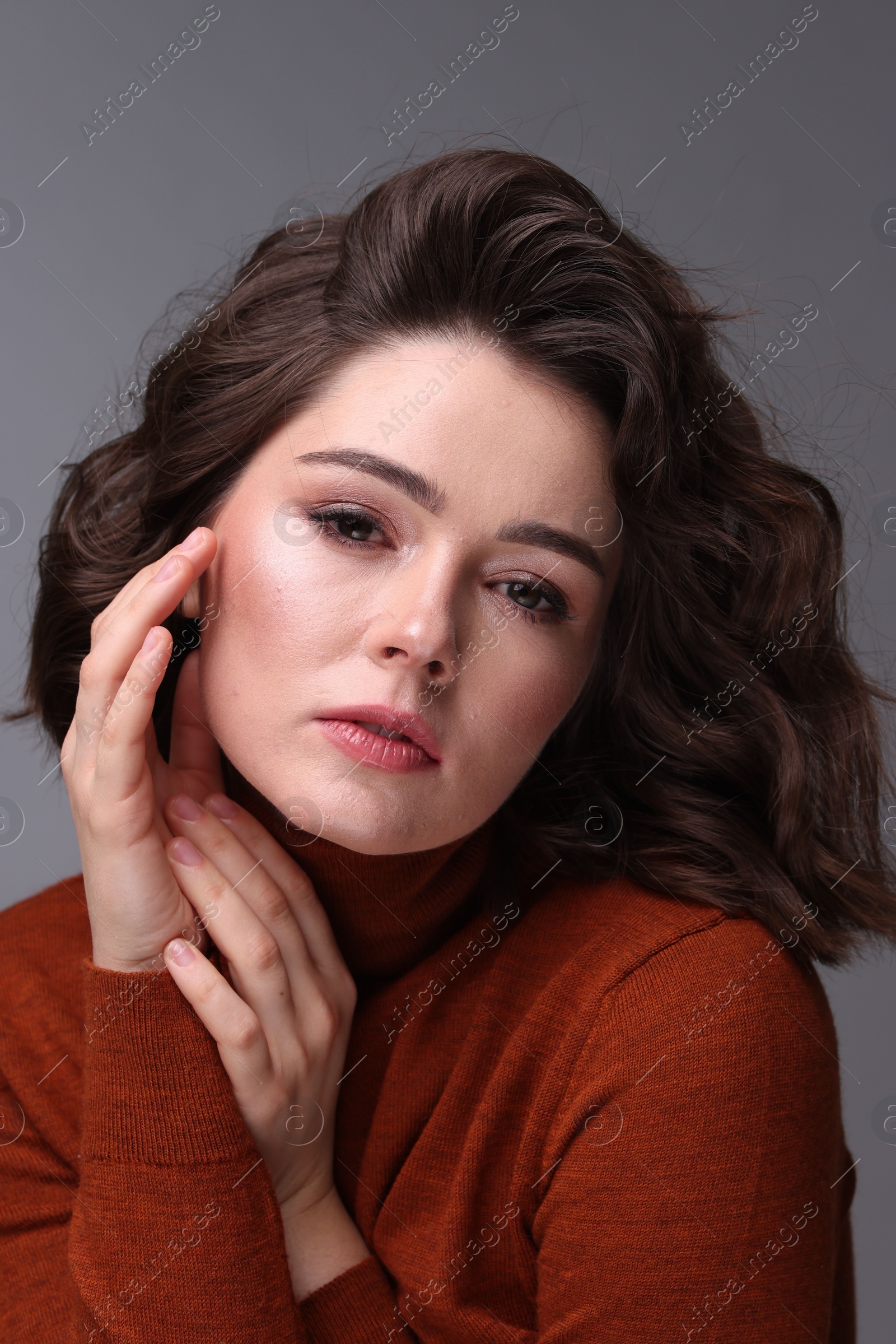 Photo of Portrait of beautiful young woman with wavy hairstyle on grey background