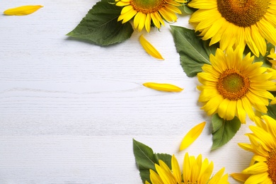Photo of Beautiful bright sunflowers and petals on white wooden background, flat lay. Space for text