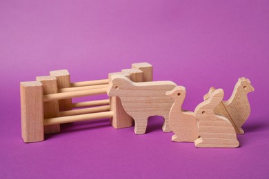 Photo of Wooden animals and fence on purple background. Children's toy