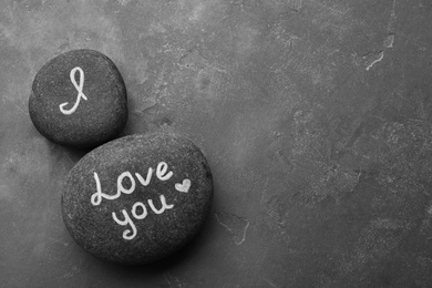 Photo of Pebbles with words I LOVE YOU and little heart on grey table, flat lay. Space for text