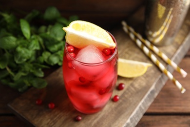 Photo of Tasty refreshing cranberry cocktail and fresh ingredients on wooden table, closeup