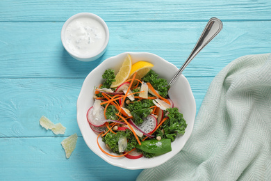 Photo of Tasty fresh kale salad on light blue wooden table, flat lay