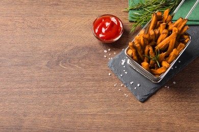 Photo of Frying basket with sweet potato fries and ketchup on wooden table, above view. Space for text