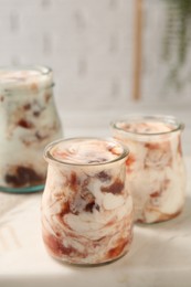 Photo of Tasty yoghurt with jam on white marble board, closeup