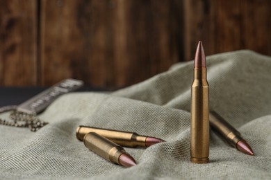 Photo of Many brass bullets on burlap, closeup. Space for text