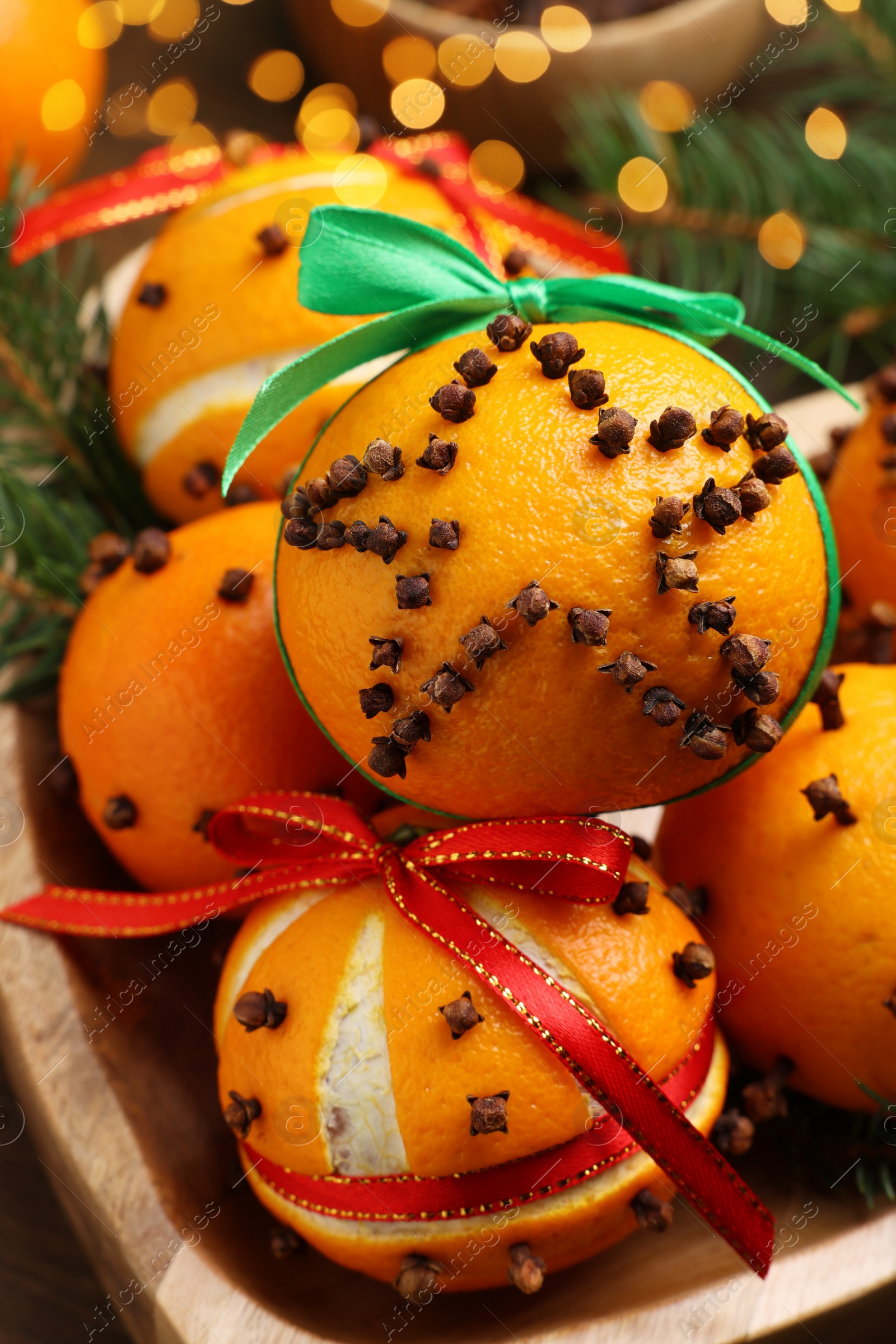 Photo of Pomander balls made of tangerines with cloves and fir branches on table, closeup