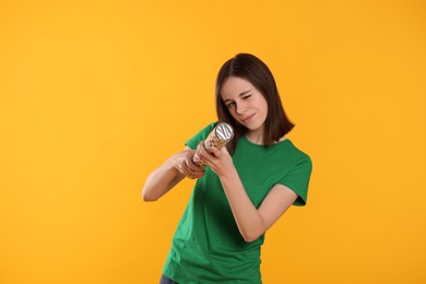 Beautiful teenage girl with party popper on orange background