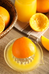 Photo of Squeezer and cut fresh oranges on wooden table