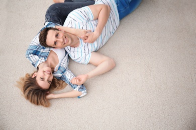 Lovely young couple lying on cozy carpet at home