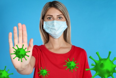 Image of Stop Covid-19 outbreak. Woman wearing medical mask surrounded by virus on blue background