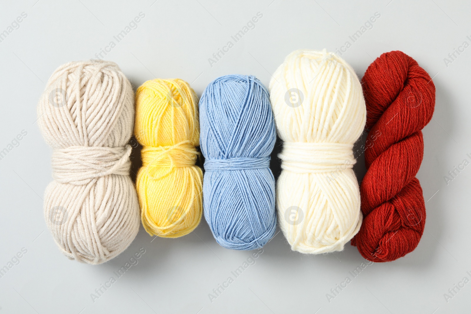 Photo of Soft colorful woolen yarns on white background, flat lay