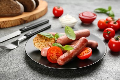 Photo of Delicious vegetarian sausages with basil and vegetables on grey table
