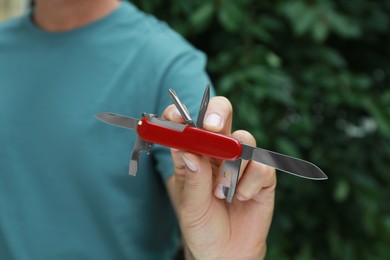 Photo of Man holding compact portable multitool outdoors, closeup