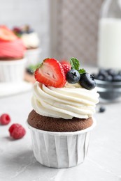 Photo of Sweet cupcake with fresh berries on light table