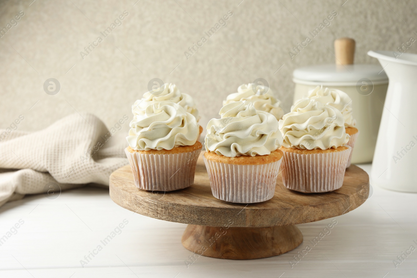 Photo of Tasty vanilla cupcakes with cream on white wooden table