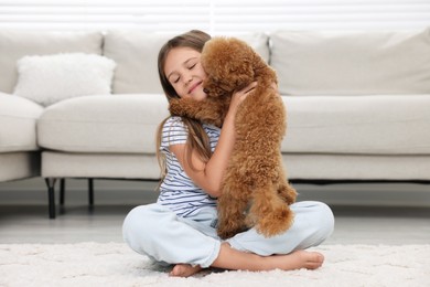 Photo of Little child with cute puppy on carpet at home. Lovely pet