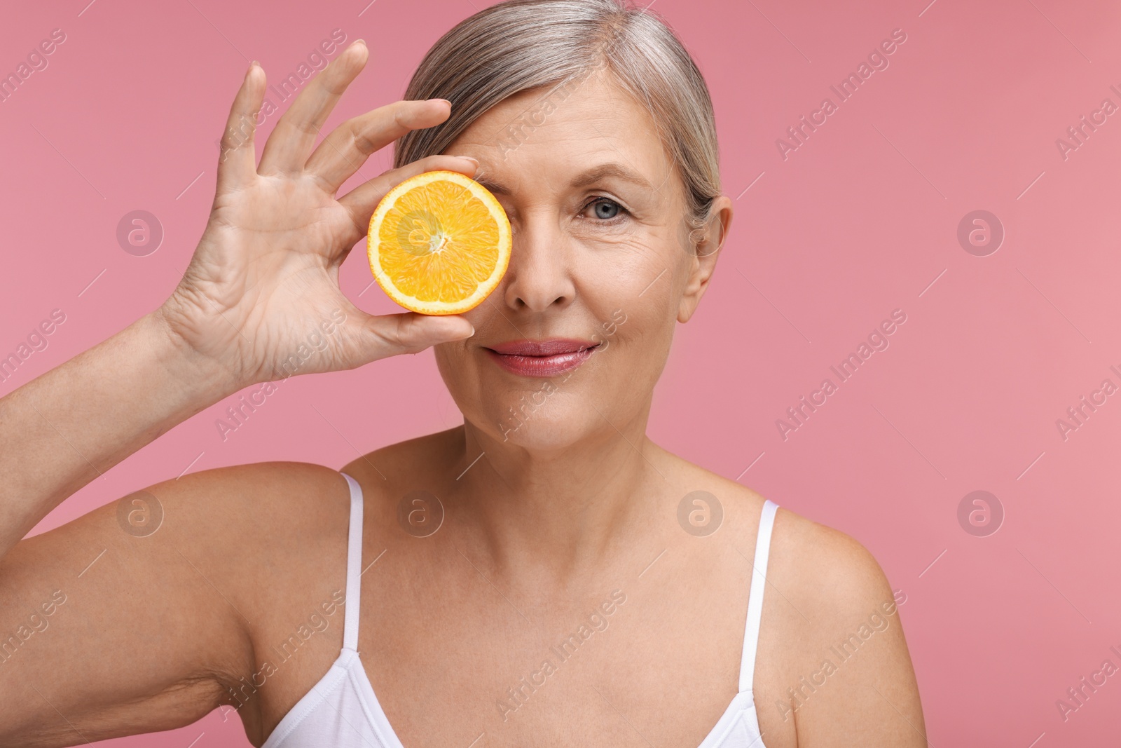 Photo of Beautiful woman with half of orange rich in vitamin C on pink background