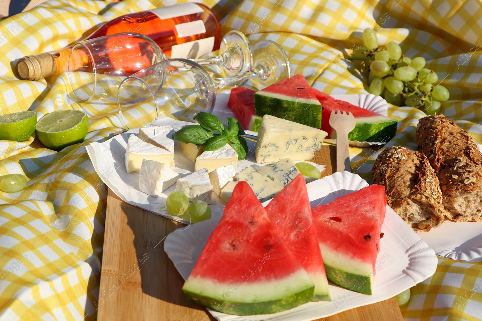 Photo of Delicious food and wine on picnic blanket, closeup