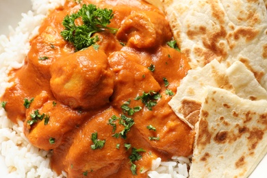 Photo of Delicious butter chicken with rice and naan as background, closeup