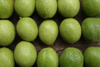 Many green walnuts on wooden table, flat lay