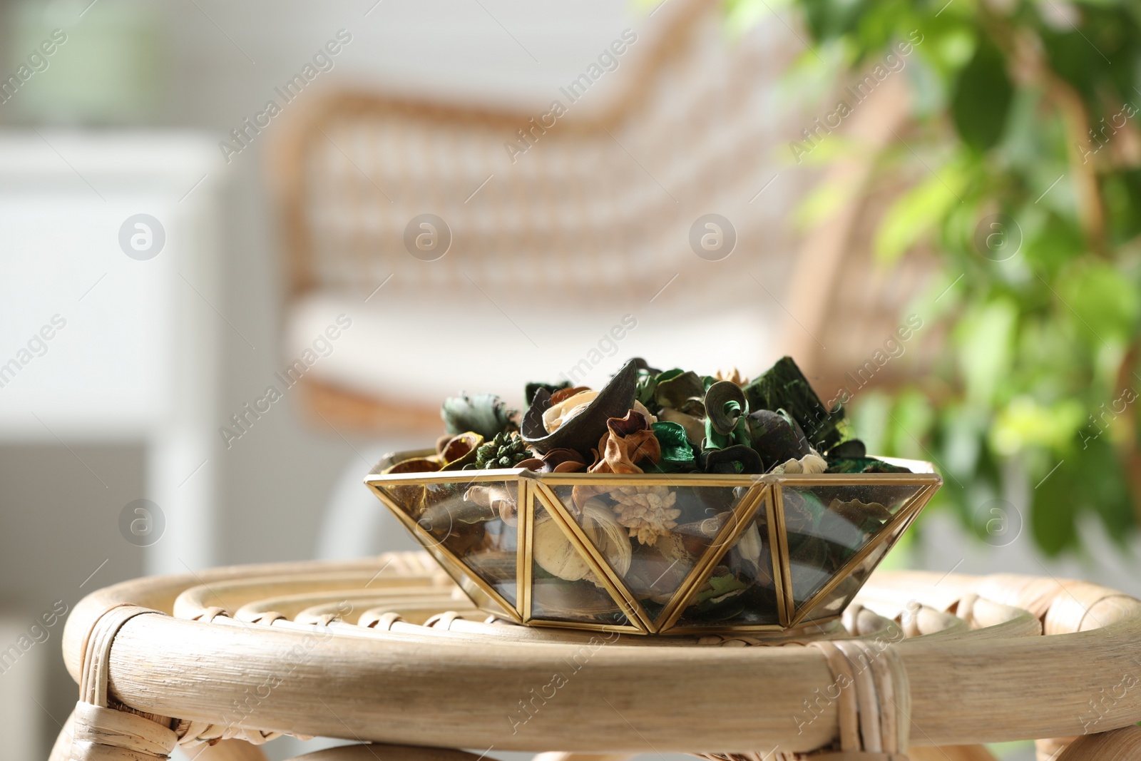 Photo of Aromatic potpourri of dried flowers in bowl on wicker table indoors