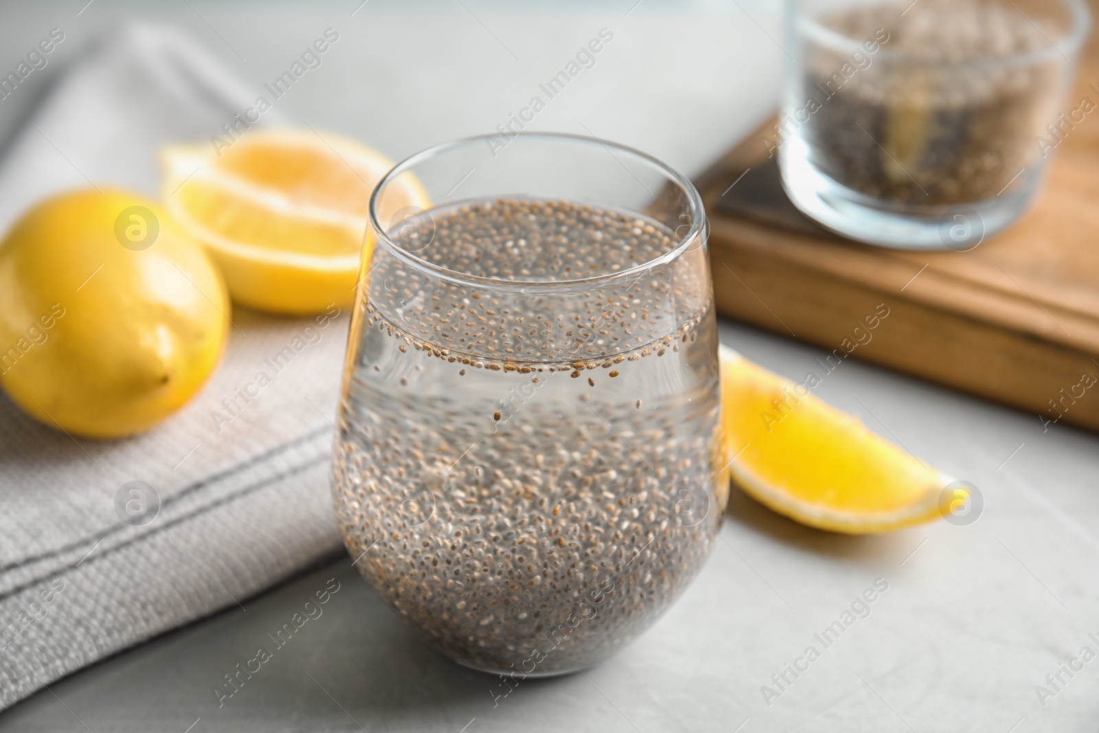 Photo of Composition with glass of water, chia seeds and lemon on table