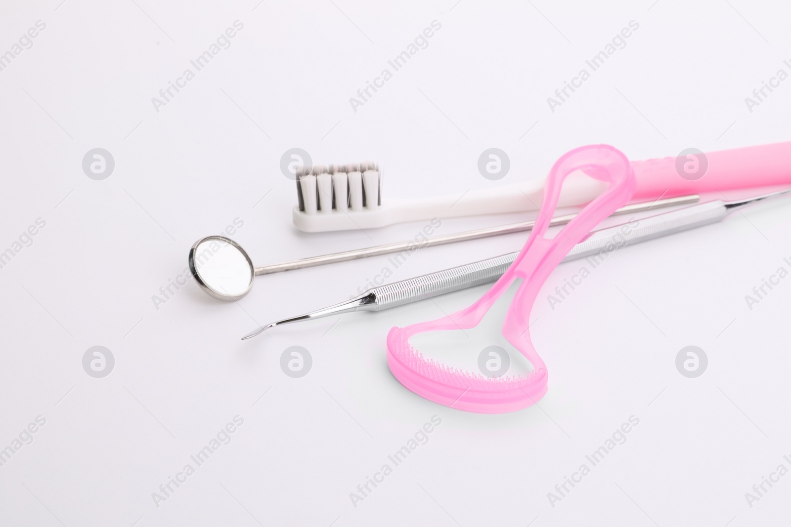 Photo of New tongue cleaner, toothbrush and dental instruments on white background