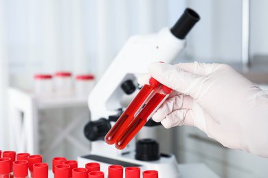 Photo of Scientist holding test tubes with blood samples in laboratory, closeup. Virus research