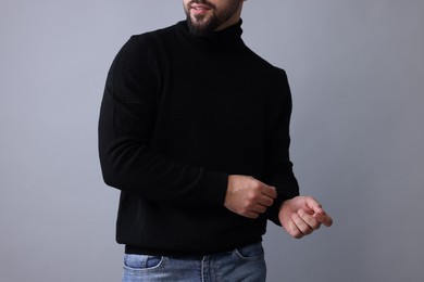 Photo of Man in stylish black sweater on grey background, closeup