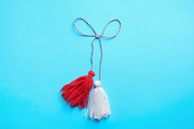 Traditional martisor on light blue background, top view. Beginning of spring celebration