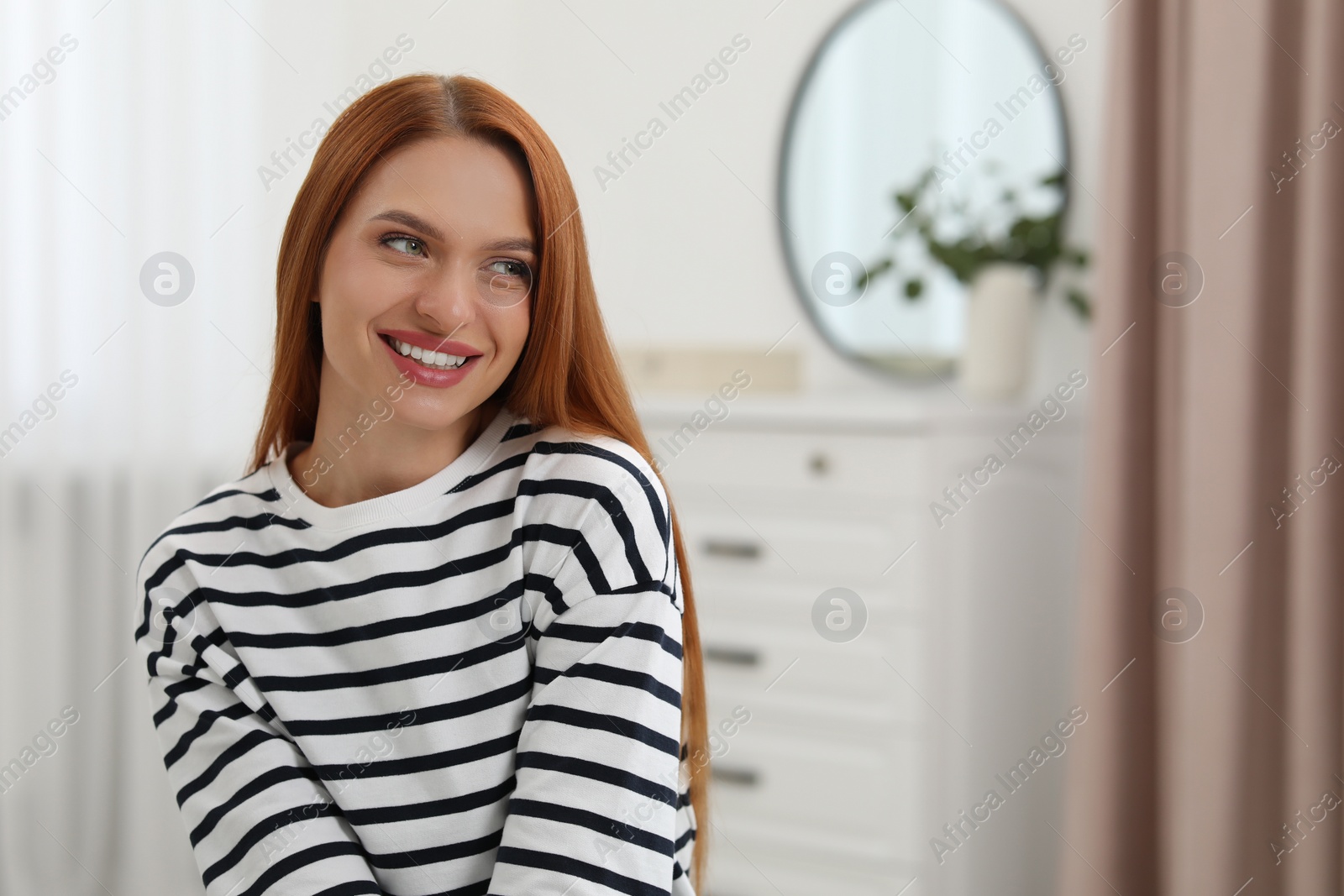Photo of Portrait of beautiful smiling young woman. Happy lady with red hair at home. Space for text