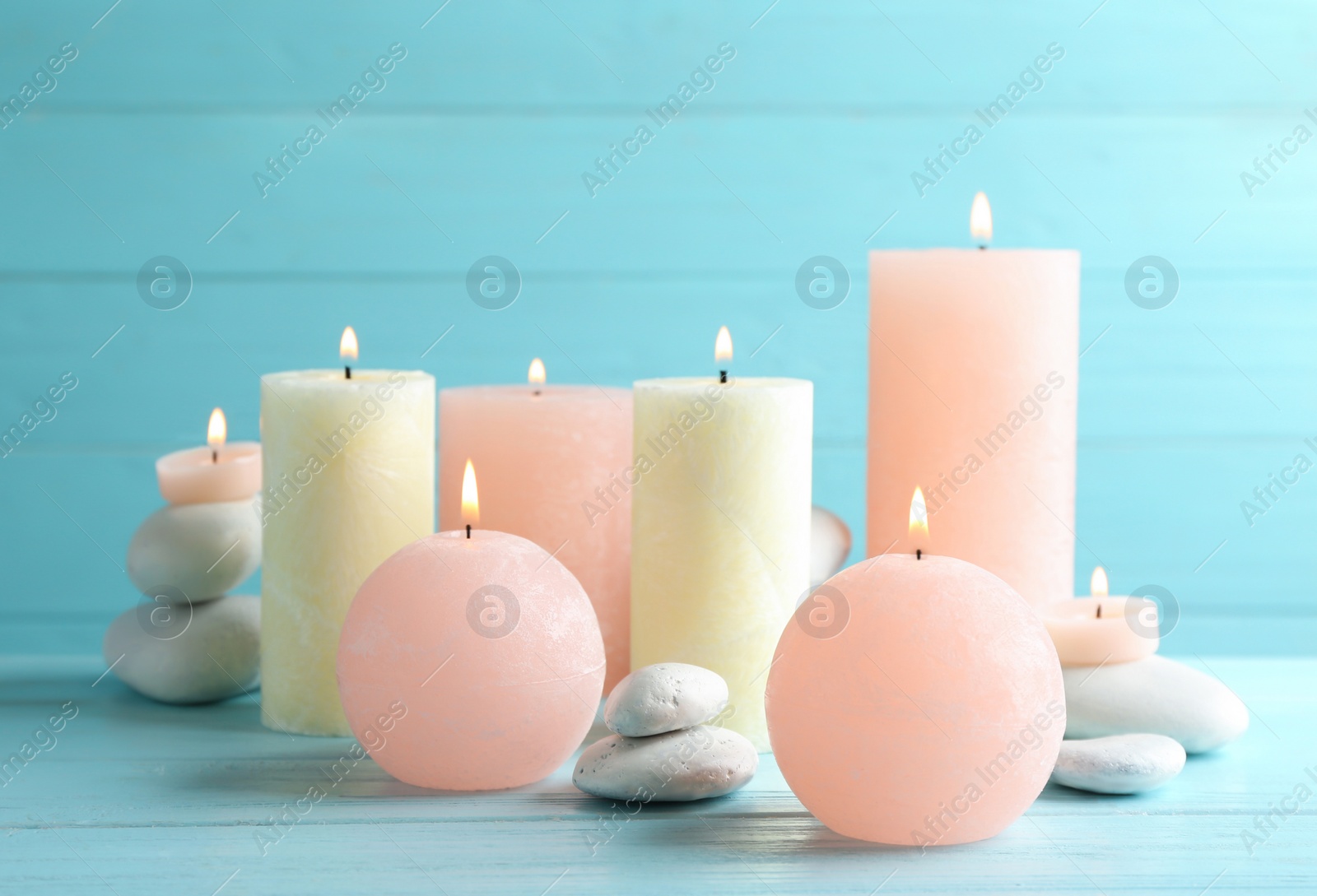 Photo of Composition of burning candles and spa stones on table