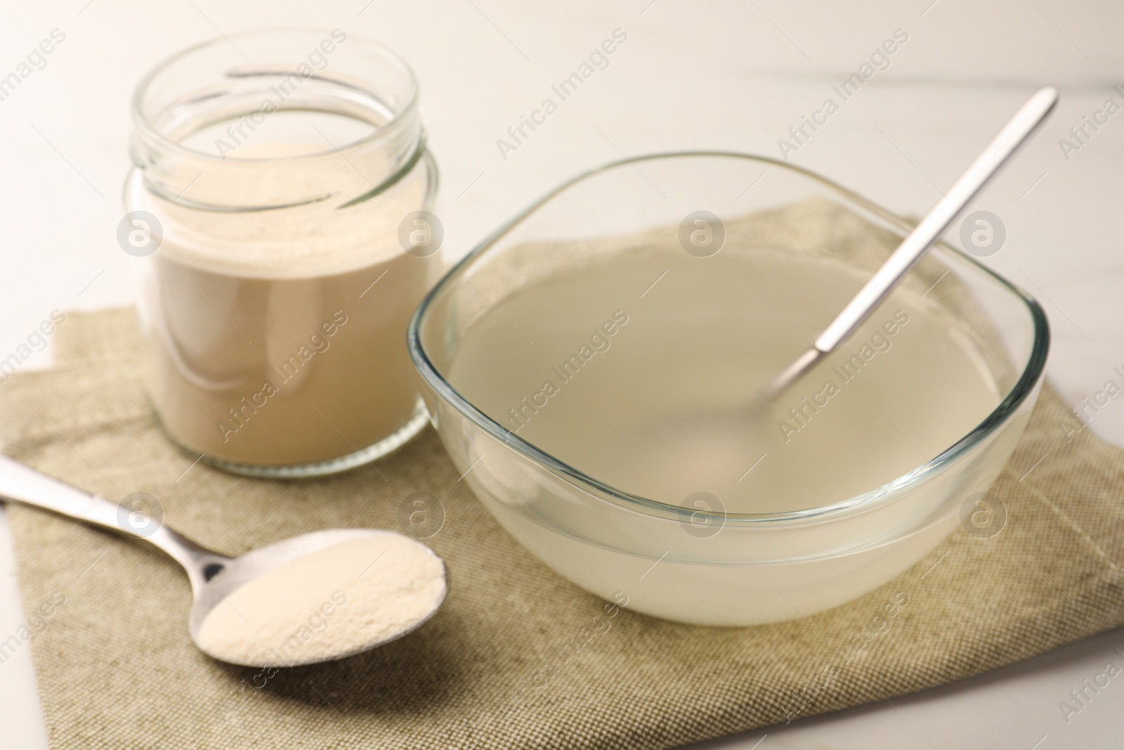 Photo of Agar-agar jelly and powder on white table, closeup