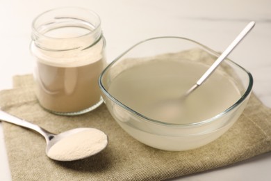 Photo of Agar-agar jelly and powder on white table, closeup