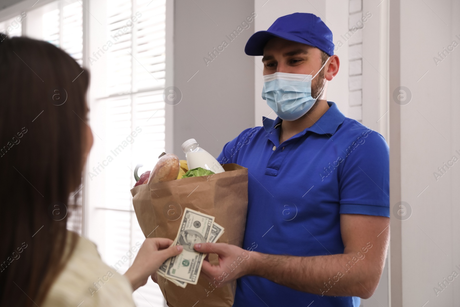 Photo of Young woman giving tips to courier indoors