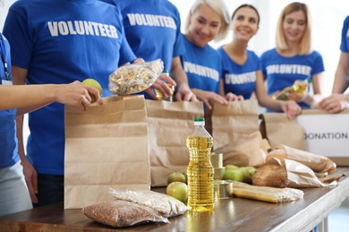 Team of volunteers collecting food donations at table, closeup