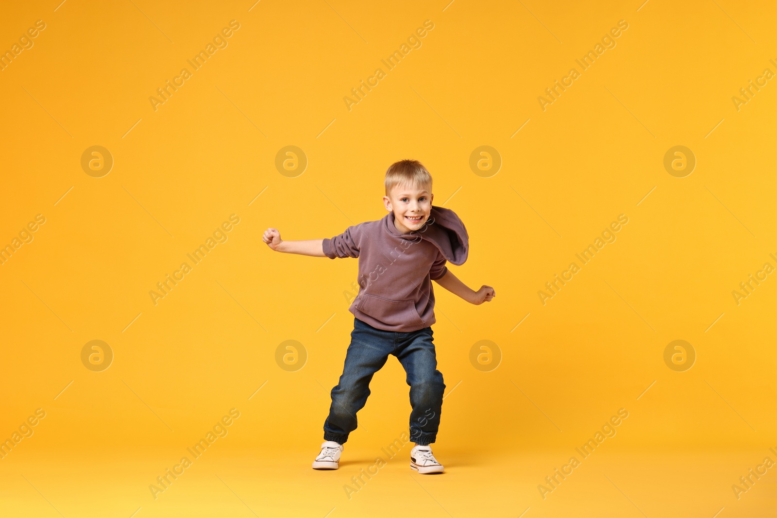 Photo of Happy little boy dancing on yellow background