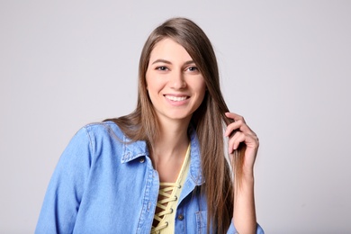 Portrait of young woman with long beautiful hair on light background