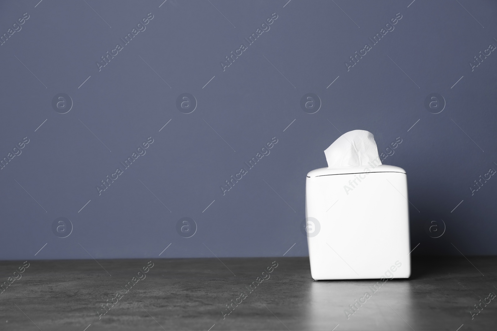 Photo of Napkin holder with paper serviettes on table against color background. Space for text